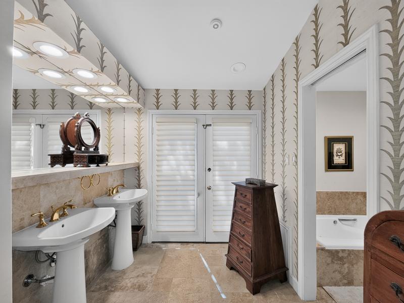 Bathroom with double sinks, patterned wallpaper, and a bathtub.