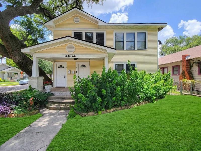 Yellow two-story home with a front porch, shade tree, and lawn.