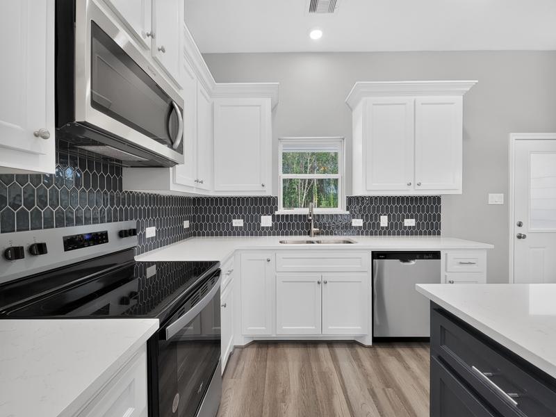 White kitchen with a dark hexagonal backsplash and stainless range.