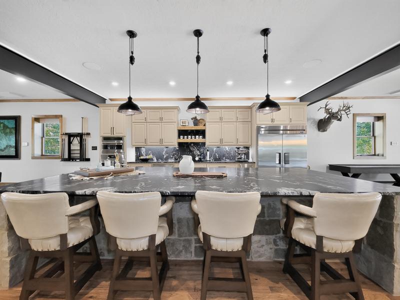 Kitchen with a large island, bar stools, and dark pendant lights.