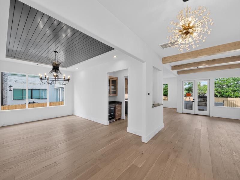 Bright open living area with a vaulted wood ceiling, beams, and chandelier.