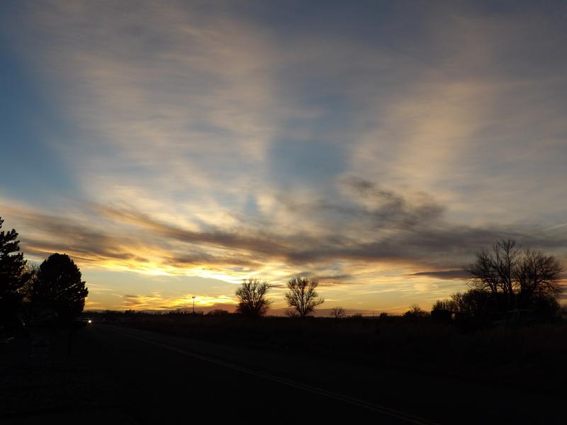 Montana road at dusk with a glowing sunset sky and silhouetted trees