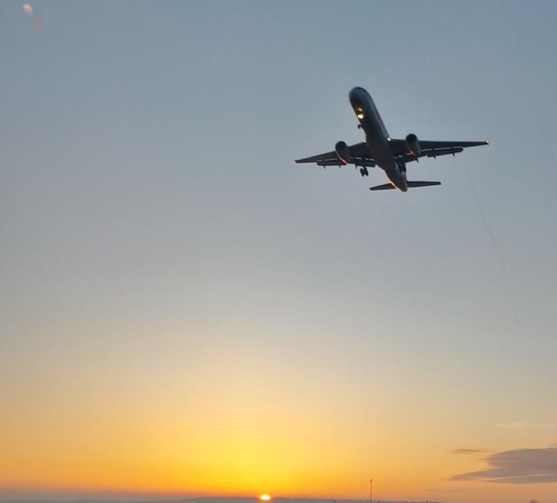Silhouette of a small airplane flying through a warm Montana sunset