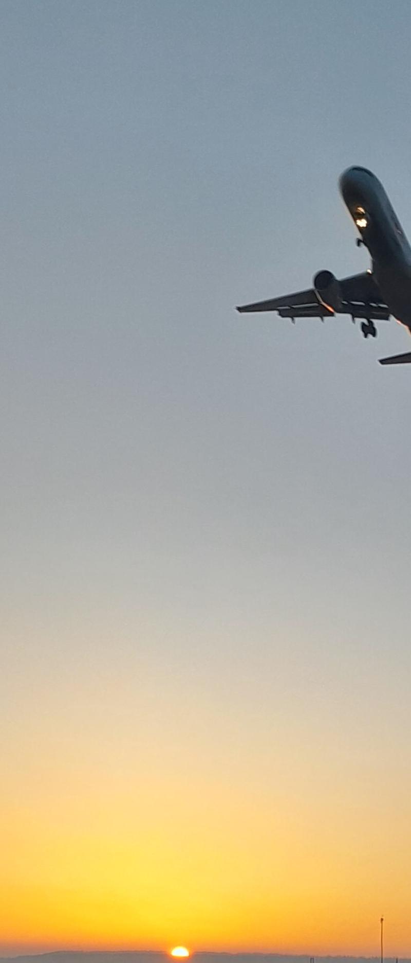 Silhouette of a small airplane flying through a warm Montana sunset