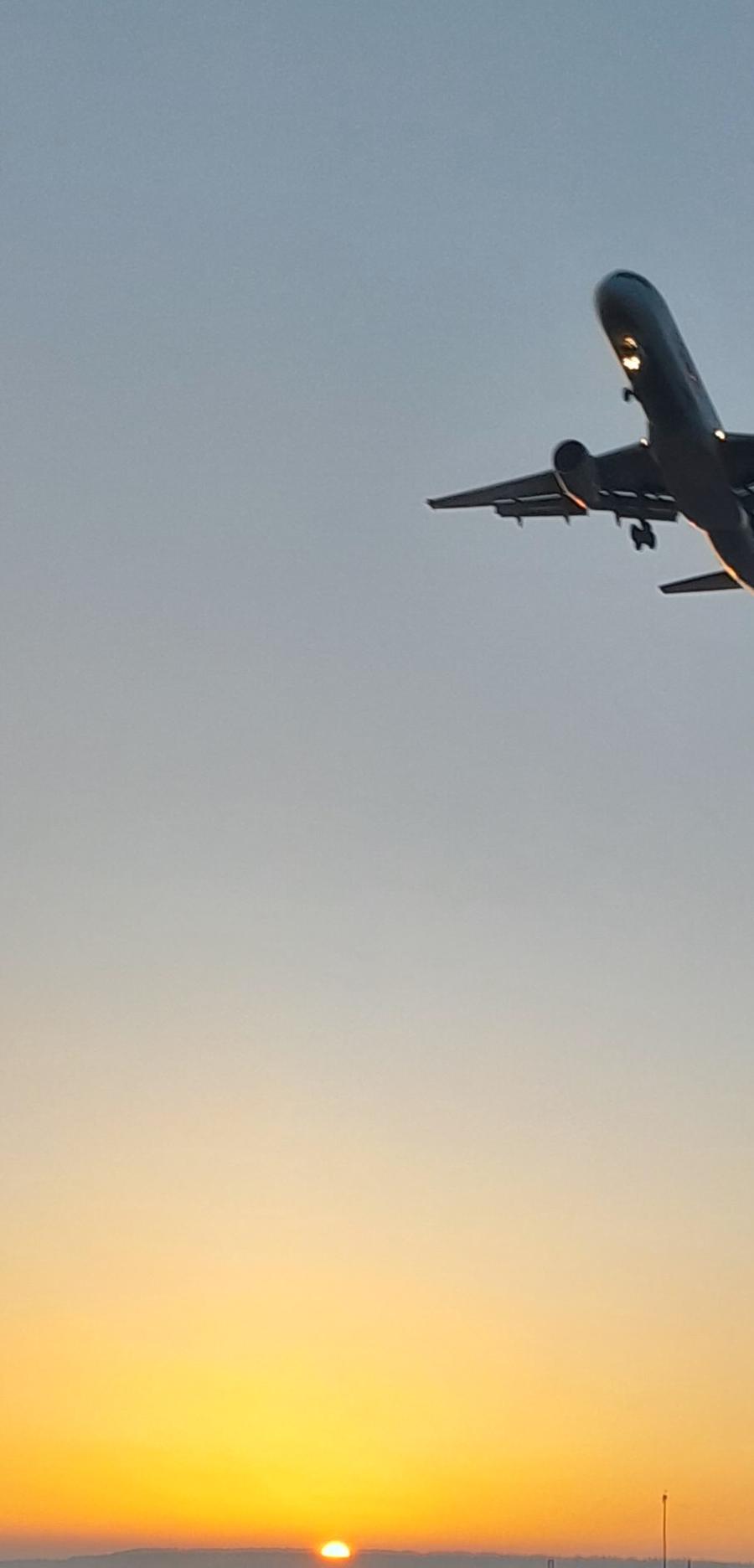 Silhouette of a small airplane flying through a warm Montana sunset