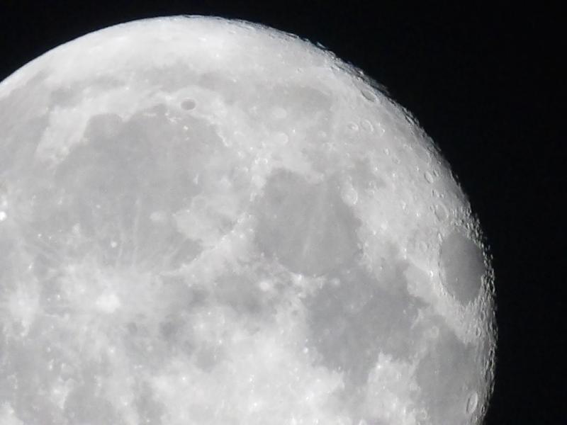 Close view of the moon's pale cratered surface against a black night sky