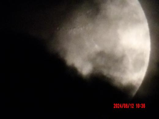 A bright moon emerging through dark cloud cover